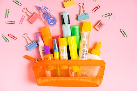A vibrant collection of office supplies in an orange pouch against a pink background.