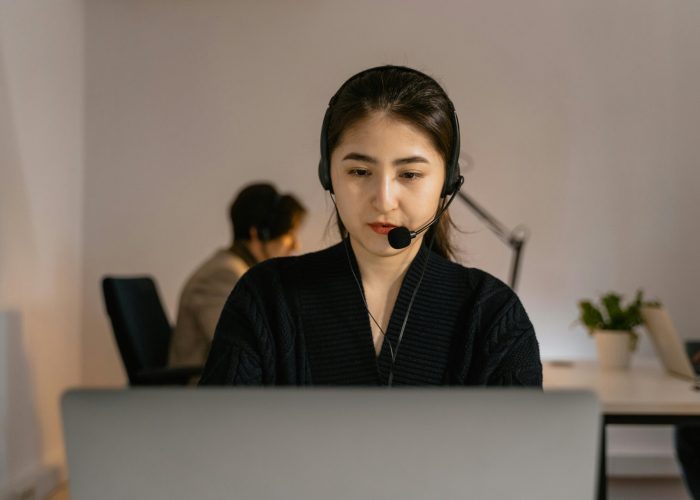 Professional call center agent in headphones diligently working on a computer indoors.